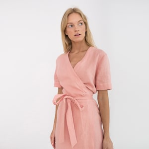 Op de afbeelding: Een roze linnen wikkeljurk met korte mouwen en een strikceintuur.