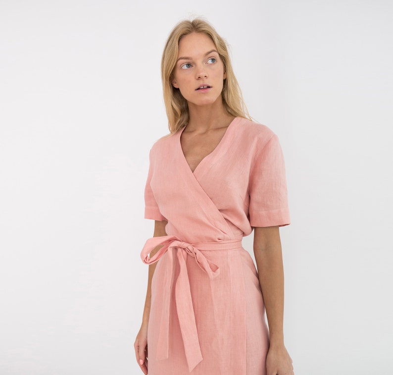 Op de afbeelding: Een roze linnen wikkeljurk met korte mouwen en een strikceintuur.