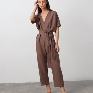 May include: A brown linen jumpsuit with a wrap-style bodice and a self-tie belt. The jumpsuit has short sleeves and a wide leg.
