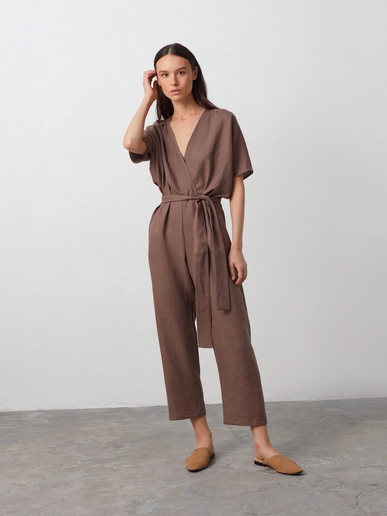 May include: A brown linen jumpsuit with a wrap-style bodice and a self-tie belt. The jumpsuit has short sleeves and a wide leg.