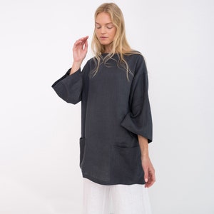 May include: A charcoal gray linen tunic with a relaxed fit and long sleeves. The tunic has two large patch pockets on the front.