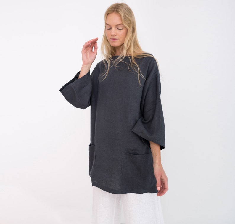 May include: A charcoal gray linen tunic with a relaxed fit and long sleeves. The tunic has two large patch pockets on the front.