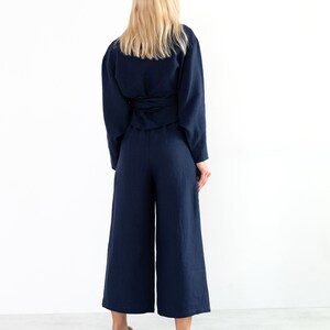 May include: A navy blue linen wrap top and wide-leg pants set. The top has a tie at the waist and the pants have a wide leg.