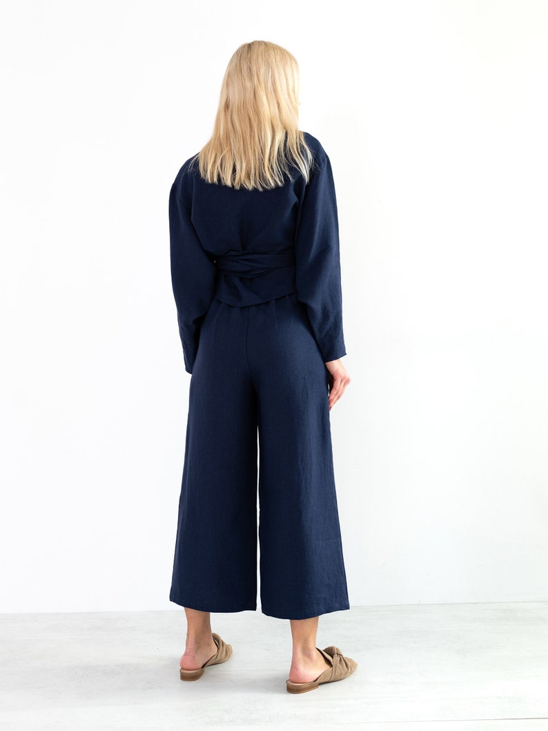 May include: A navy blue linen wrap top and wide-leg pants set. The top has a tie at the waist and the pants have a wide leg.