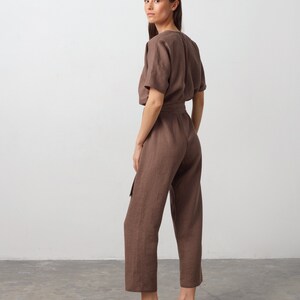 May include: A brown linen jumpsuit with a short sleeve top and a tie belt. The jumpsuit has a relaxed fit and a cropped leg.