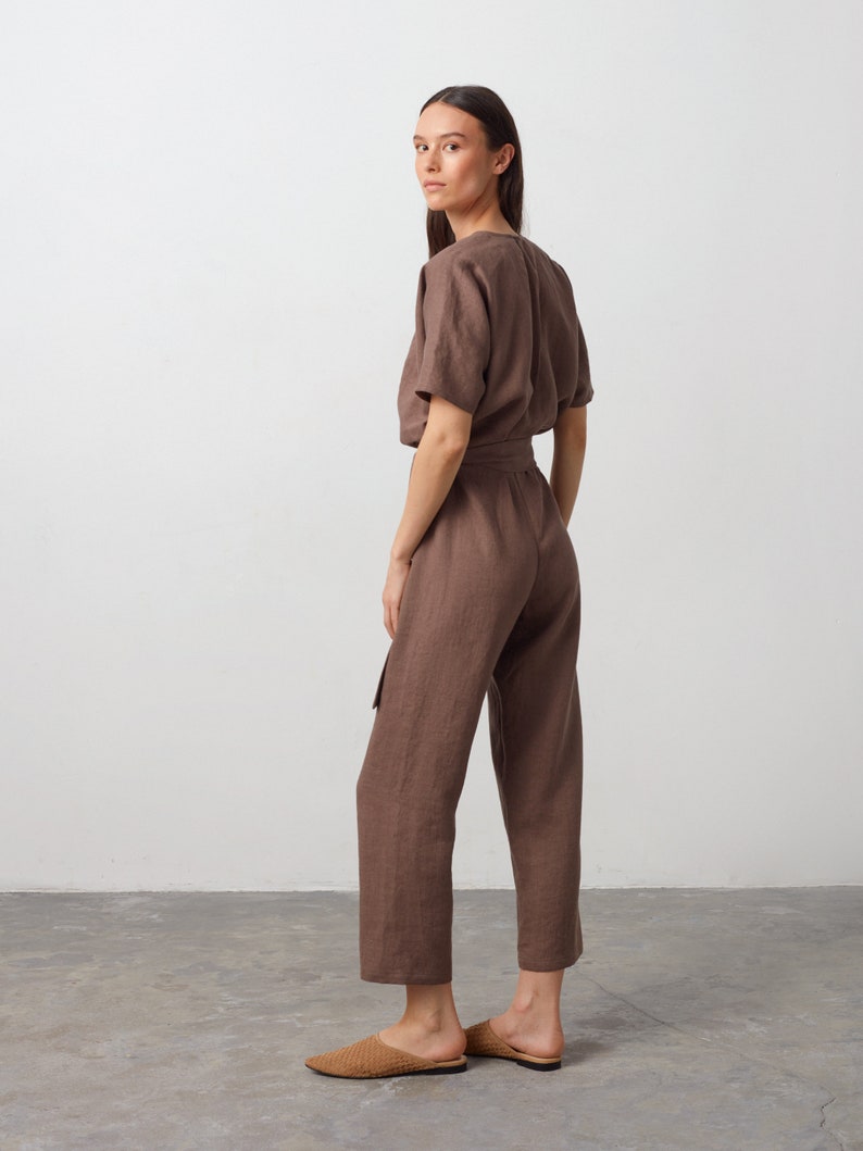 May include: A brown linen jumpsuit with a short sleeve top and a tie belt. The jumpsuit has a relaxed fit and a cropped leg.