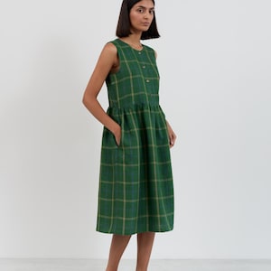 Close-up three-quarter view of the FERN dress bodice showing the round neckline, button closure, and green check linen pattern with blue and gold lines