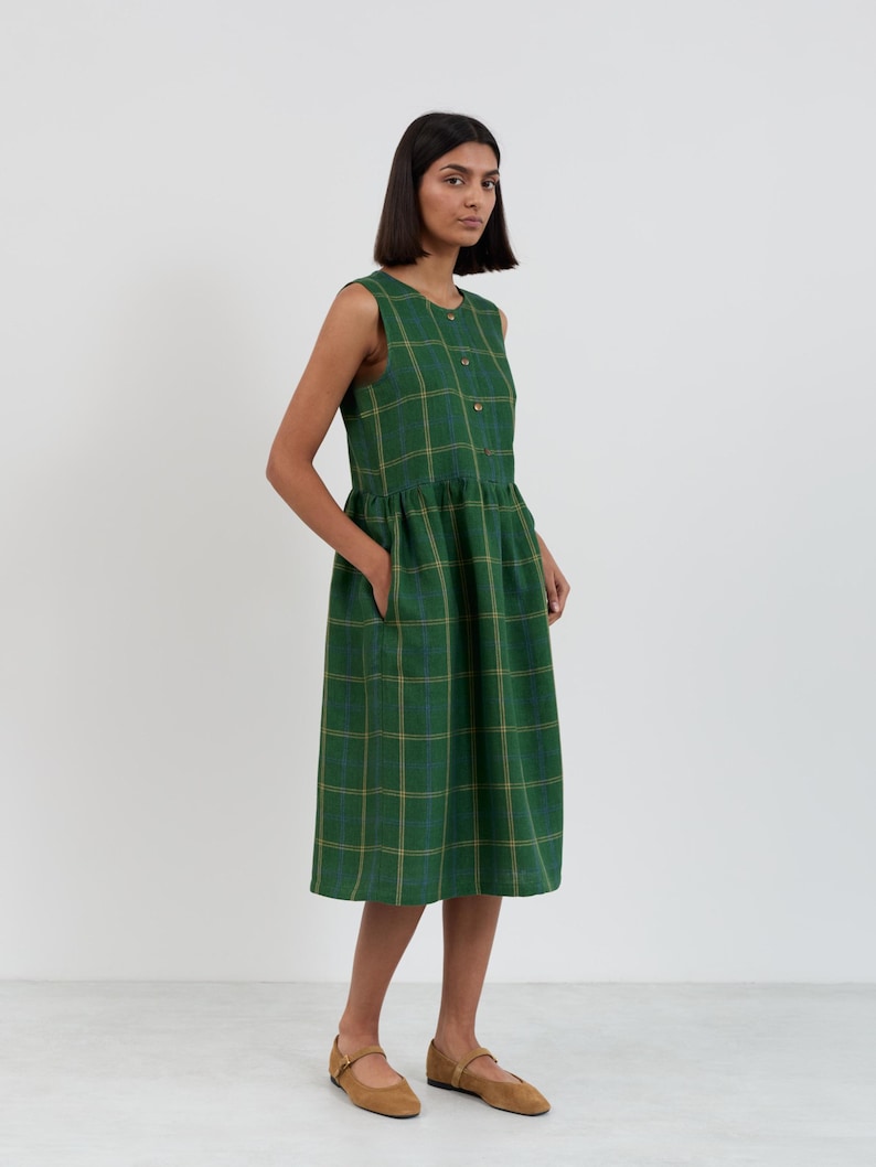Close-up three-quarter view of the FERN dress bodice showing the round neckline, button closure, and green check linen pattern with blue and gold lines