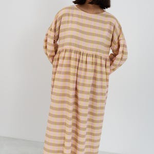 K&ouml;nnte beinhalten: Ein lang&auml;rmeliges Midikleid mit horizontalem Streifenmuster in abwechselnden Farbt&ouml;nen von Hellrosa, ged&auml;mpftem Olivgr&uuml;n und Creme. Das Kleidungsst&uuml;ck hat einen Rundhalsausschnitt, eine geraffte Taillennaht und volumin&ouml;se &Auml;rmel mit B&uuml;ndchen.