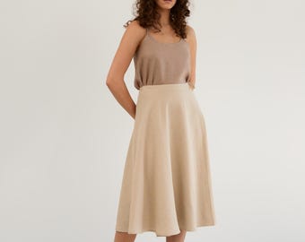 May include: A beige linen skirt with a flowy A-line silhouette. The skirt is knee-length and has a high waist.