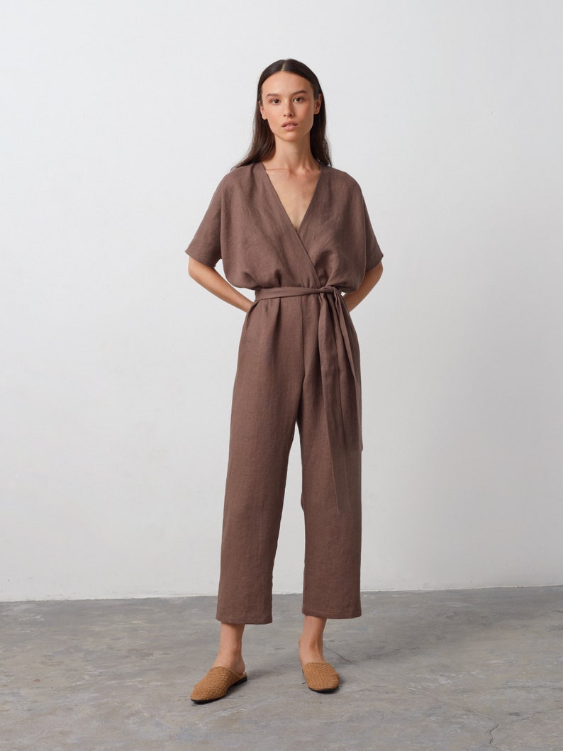 May include: A brown linen jumpsuit with a wrap-style bodice and a tie belt. The jumpsuit has short sleeves and a V-neckline.