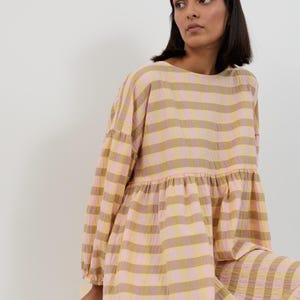 K&ouml;nnte beinhalten: Ein lang&auml;rmeliges Kleid mit einem horizontalen Streifenmuster in abwechselnden Farbt&ouml;nen von hellem Rosa und ged&auml;mpftem Olivgr&uuml;n. Das Kleidungsst&uuml;ck hat einen Rundhalsausschnitt, eine geraffte Taillennaht und lange &Auml;rmel mit elastischen B&uuml;ndchen.