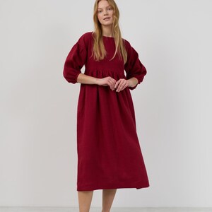 May include: A long-sleeved, burgundy midi dress with a gathered skirt and puffed sleeves.