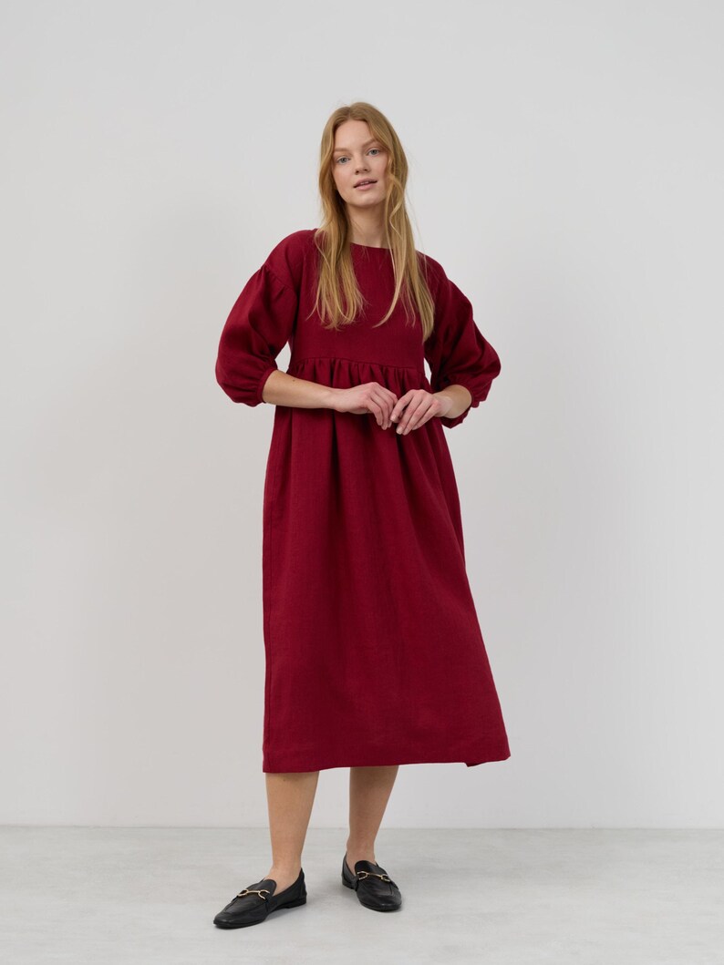 May include: A long-sleeved, burgundy midi dress with a gathered skirt and puffed sleeves.