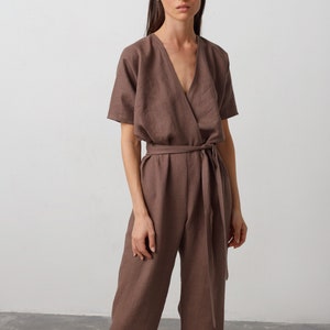 May include: A brown linen jumpsuit with a wrap-style bodice and a self-tie belt. The jumpsuit has short sleeves and a V-neckline.