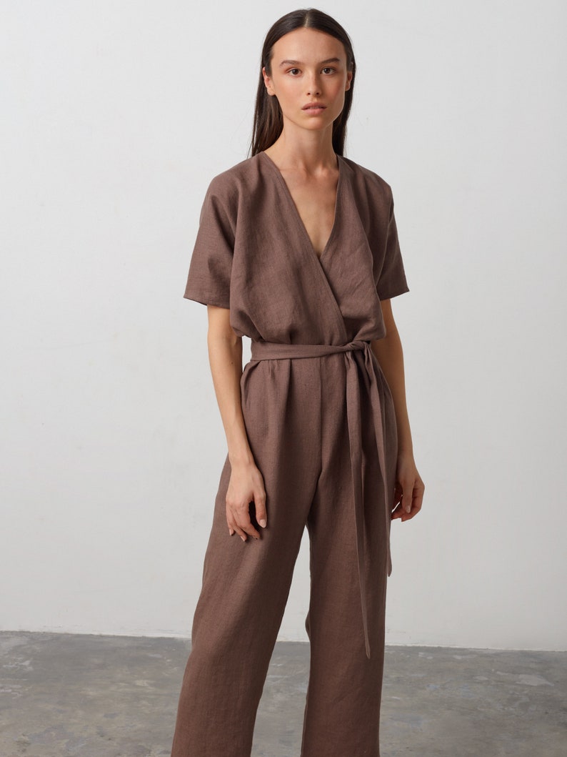 May include: A brown linen jumpsuit with a wrap-style bodice and a self-tie belt. The jumpsuit has short sleeves and a V-neckline.