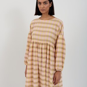 K&ouml;nnte beinhalten: Ein lang&auml;rmeliges Midikleid mit einem horizontalen Streifenmuster in abwechselnden Farbt&ouml;nen von Hellrosa und ged&auml;mpftem Olivgr&uuml;n. Das Kleidungsst&uuml;ck hat einen Rundhalsausschnitt, eine geraffte Taille und weite &Auml;rmel mit elastischen B&uuml;ndchen.