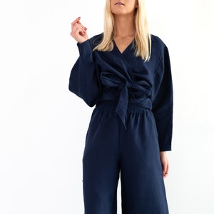 May include: A navy blue linen wrap top and wide-leg pants set. The top has a V-neckline and ties at the waist. The pants have a relaxed fit and a drawstring waist.