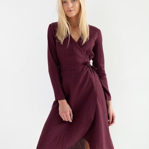 Pu&ograve; includere: Un abito avvolgente color bordeaux con maniche lunghe e cintura a nodo. L'abito ha una scollatura a V e una lunghezza midi.