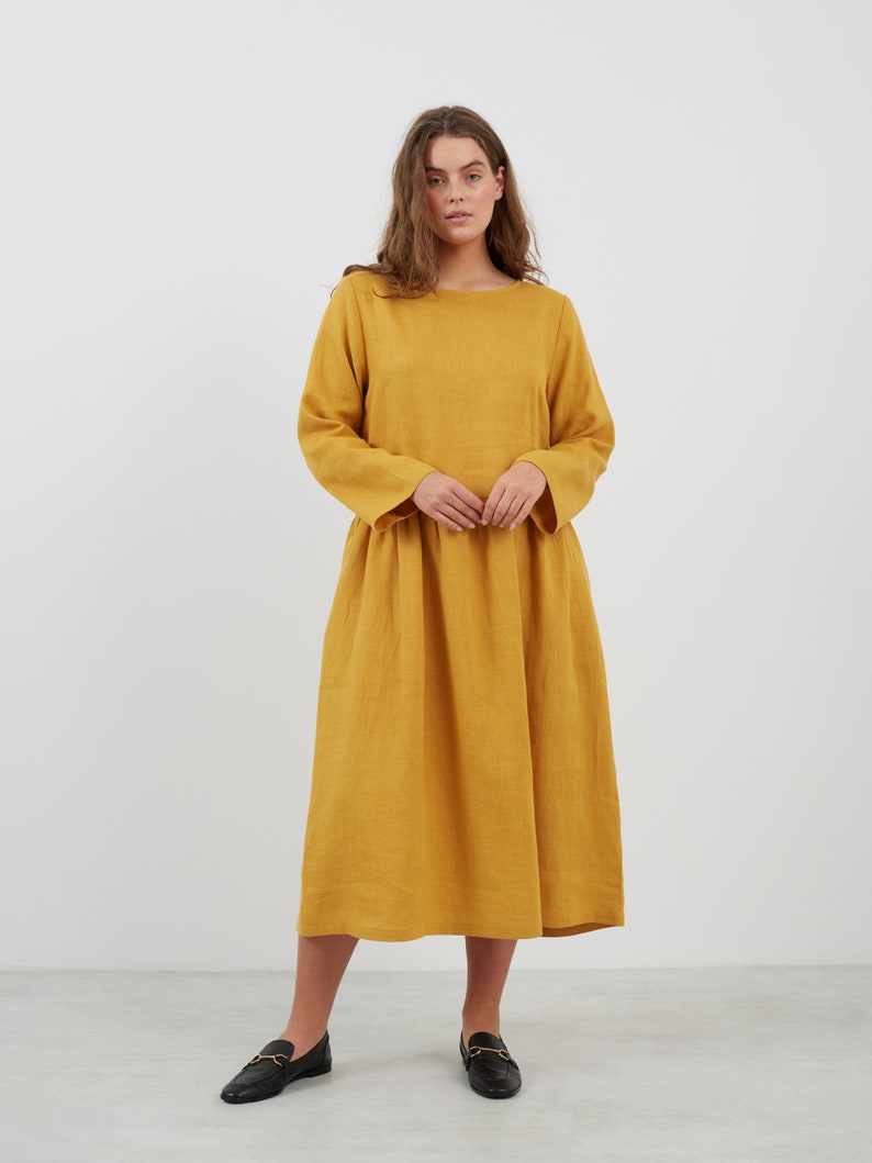 May include: A long-sleeved, mustard yellow linen dress with a loose fit and a boat neckline.