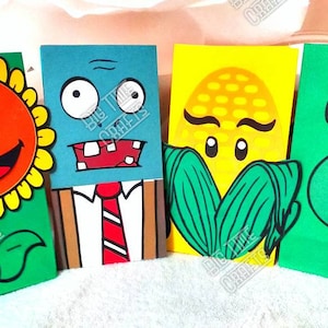 May include: Four colorful paper bags decorated with characters from the Plants vs. Zombies video game. The bags feature a sunflower, a zombie, a corn, and a pea shooter. Each bag has the text "Big Time Crafts" printed on it.