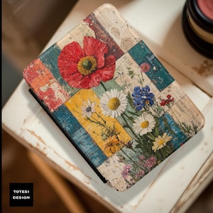 May include: A floral-themed notebook with a colorful patchwork design. The cover features a large red poppy, daisies, and other wildflowers. The notebook has a black spine and the text "TOTESI DESIGN" is visible.