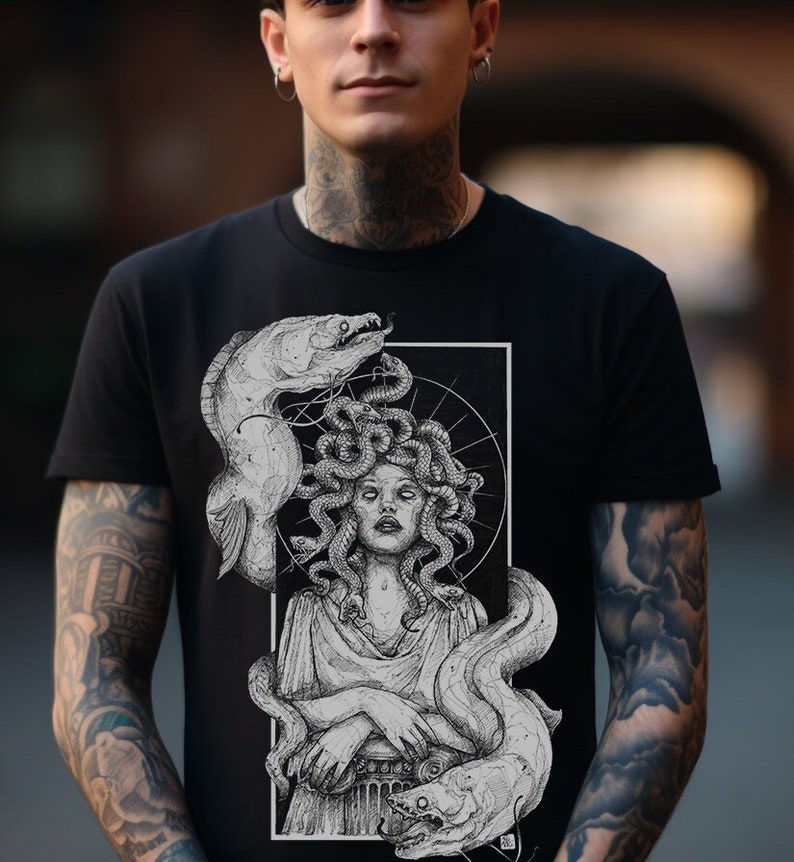 Op de afbeelding: Zwart T-shirt met een grafische print van Medusa, een mythische Griekse figuur met slangenhaar, omringd door paling. De print is in zwart en wit.