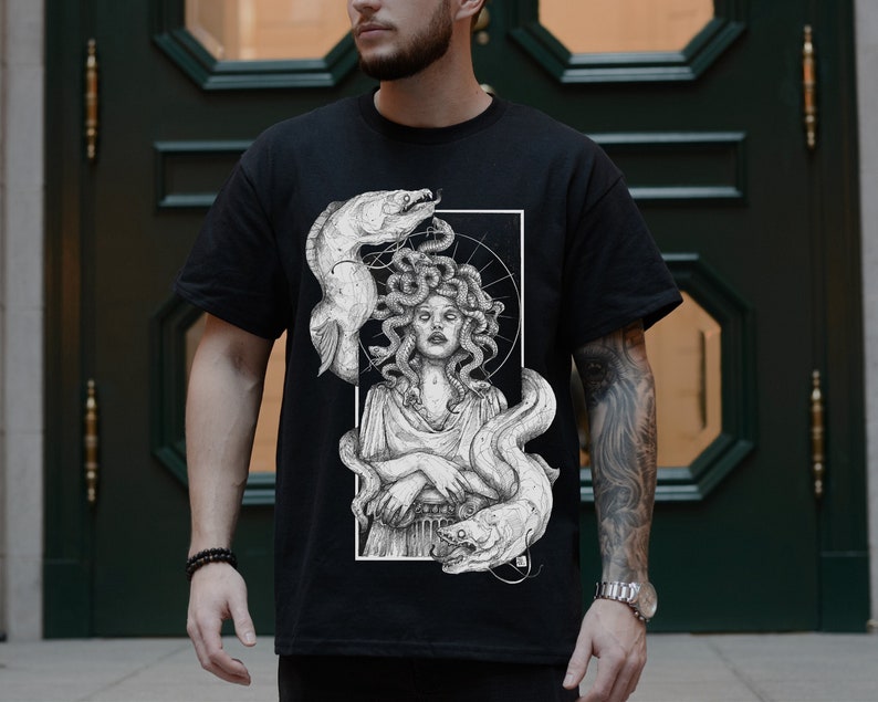 Op de afbeelding: Zwart T-shirt met een witte grafische print van Medusa, een mythische Griekse figuur met slangenhaar, omringd door paling.