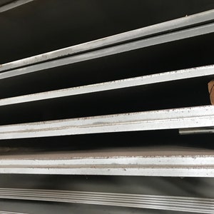 May include: Close-up of a stack of metal sheets. The sheets are smooth and have a slight sheen. The edges of the sheets are visible, and they appear to be cut cleanly.