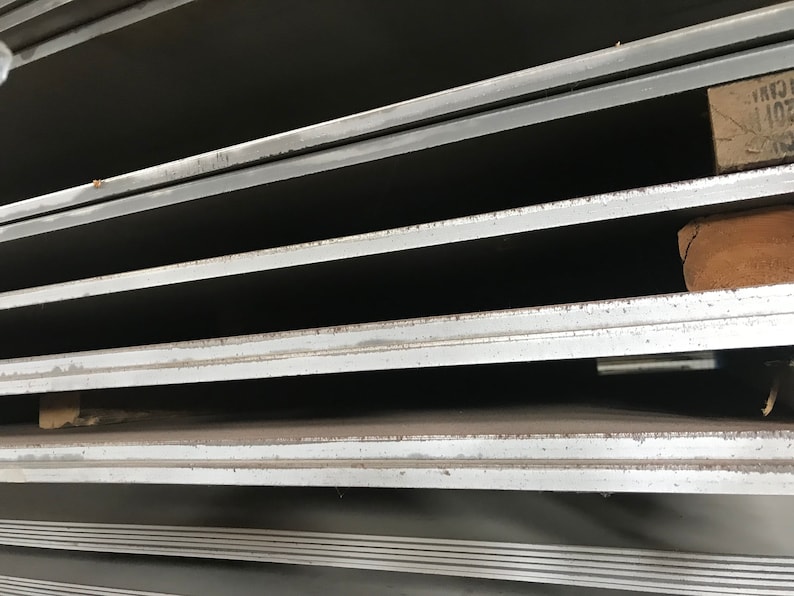 May include: Close-up of a stack of metal sheets. The sheets are smooth and have a slight sheen. The edges of the sheets are visible, and they appear to be cut cleanly.