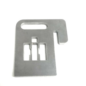 May include: A metal cutout of a gear shift pattern with the letters "IH" in the center. The cutout is designed to be used as a wall decoration or a keychain.