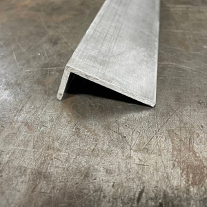 May include: A silver metal angle bracket with a smooth, brushed finish. The bracket is made of a sturdy metal and has a sharp 90-degree angle.