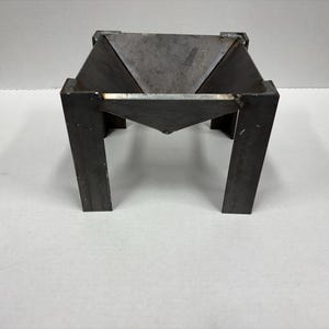 May include: A square metal fire pit with four legs and a cone-shaped fire bowl.