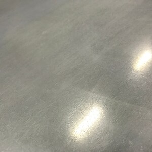 May include: A close-up of a smooth, gray concrete surface with two bright, white light reflections.