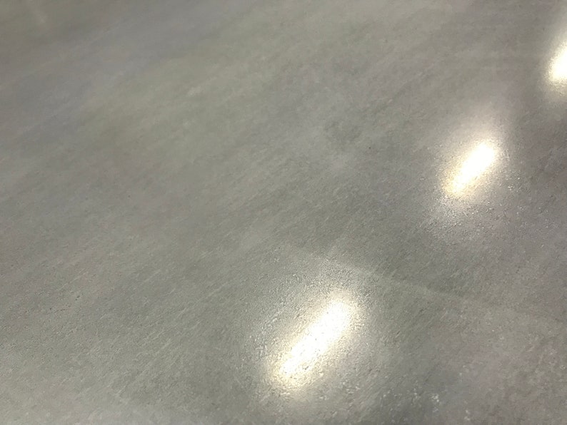May include: A close-up of a smooth, gray concrete surface with two bright, white light reflections.