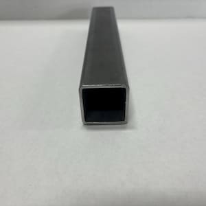 May include: A white ceramic mug with a black handle and the text "But First, Coffee" in a black, bold font. The mug is sitting on a wooden surface. The mug is 4 inches tall.