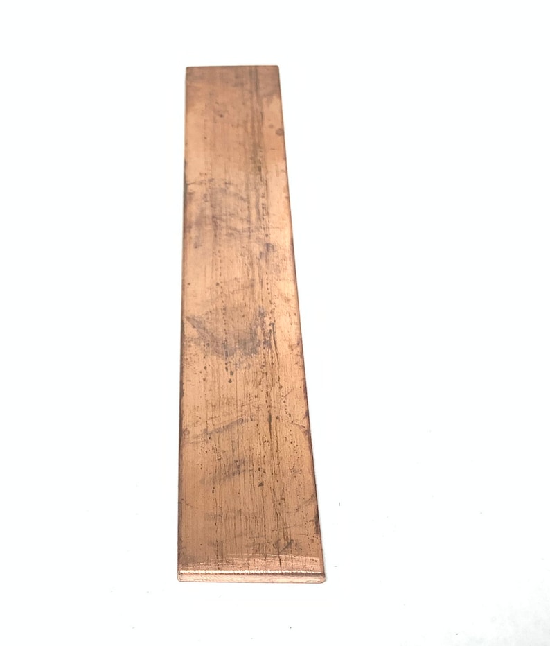 May include: A long, thin, rectangular piece of copper metal. The metal has a slightly reddish-brown color and a textured surface.