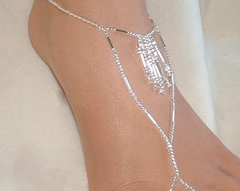 May include: Silver foot jewelry with a dangling chain and beads. The jewelry is worn on a person's foot.