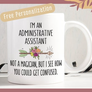 May include: White ceramic coffee mug with a black and brown arrow with flowers and the text "I'm an Administrative Assistant. Not a magician, but I see how you could get confused."