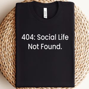 May include: Black t-shirt with white text that reads "404: Social Life Not Found."