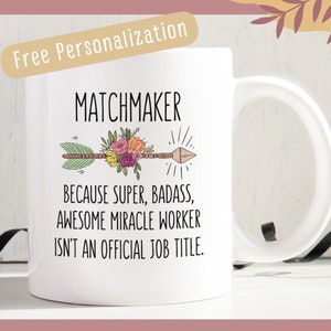 May include: White ceramic mug with a black and brown arrow with floral accents. The text "MATCHMAKER" is above the arrow and the text "BECAUSE SUPER, BADASS, AWESOME MIRACLE WORKER ISN'T AN OFFICIAL JOB TITLE." is below the arrow.