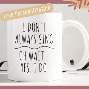 May include: White ceramic mug with the text "I DON'T ALWAYS SING OH WAIT... YES, I DO" in black. The mug has a curved handle and is set against a neutral background. The words "Free Personalization" are in a tan banner at the top.