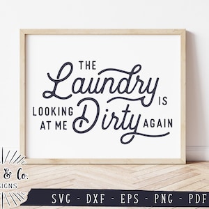 May include: A white framed print with black text that reads "The Laundry is Looking at Me Dirty Again".