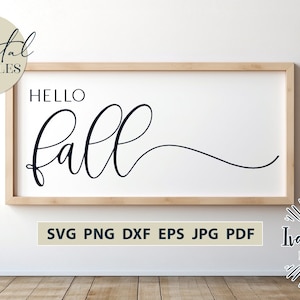 May include: A white sign with a wooden frame, featuring the text "Hello Fall" in a black cursive font. The sign is displayed against a white wall.