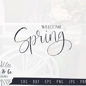 Puede incluir: Texto "Bienvenido Primavera" en una fuente cursiva con un fondo blanco y una imagen borrosa de flores y una rueda de carro en el fondo.