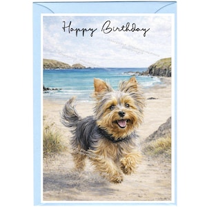 May include: A birthday greeting card featuring a Yorkshire Terrier running on a sandy beach with a blue ocean and sky in the background. The card has the words "Happy Birthday" written in black script.