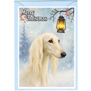 Pode incluir: Cartão de Natal com borda azul claro, apresentando um cão Saluki creme. O cartão inclui o texto "Merry Christmas". Uma lanterna pende de um galho com bagas vermelhas, em um fundo nevado.