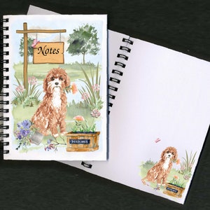 May include: A spiral bound notebook with a watercolor illustration of a brown and white dog sitting in a garden setting. The dog is holding a pink flower in its mouth. The notebook cover also features a sign that says "Notes".