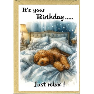 Puede incluir: Tarjeta de cumpleaños con una ilustración en acuarela de un perro golden doodle durmiendo en una cama con ropa de cama azul. La tarjeta dice "It's your Birthday..... Just relax!"