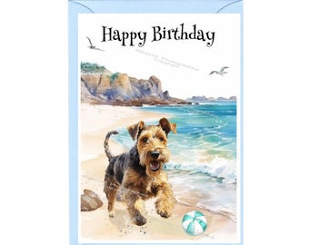 Könnte beinhalten: Eine Geburtstagskarte mit einer Aquarell-Illustration eines braunen und schwarzen Welsh Terriers, der an einem Strand mit einem blauen und weißen Strandball rennt. Die Karte trägt den Text "Happy Birthday" oben.